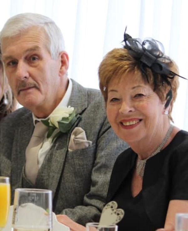 a photo of our client Mick sat with his wife at a wedding